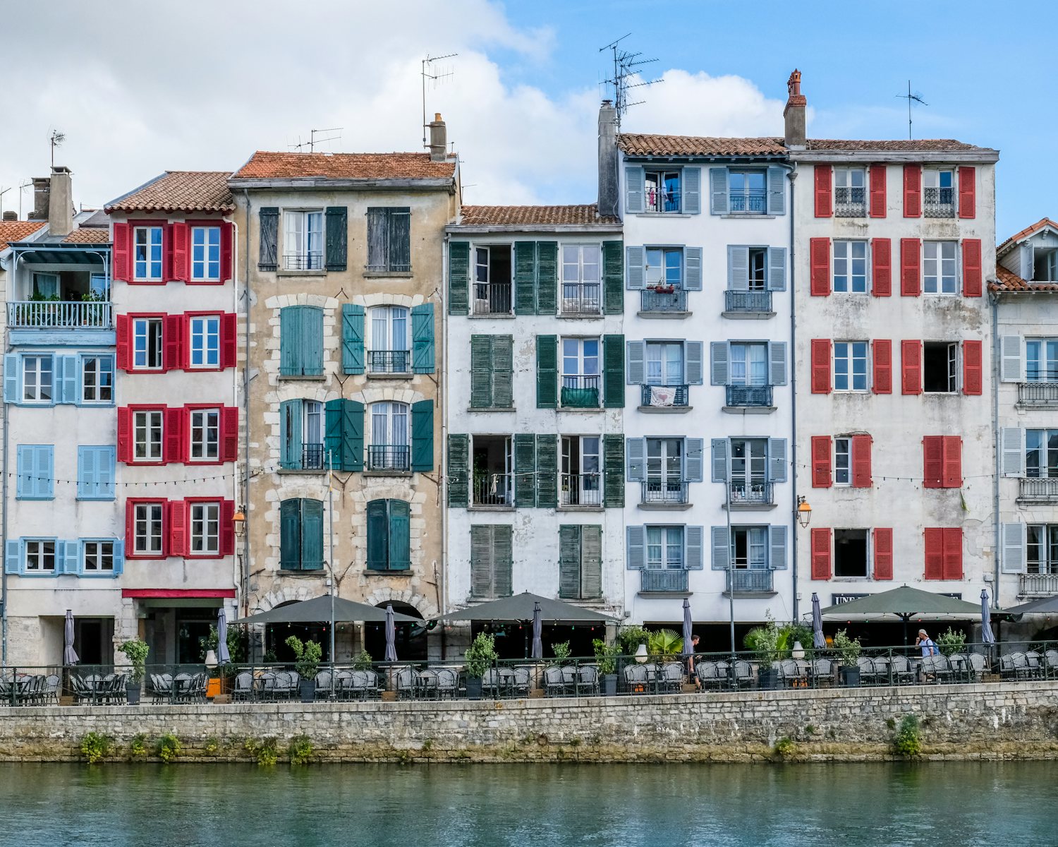 Façades colorées et terrasses sur un quai de Bayonne