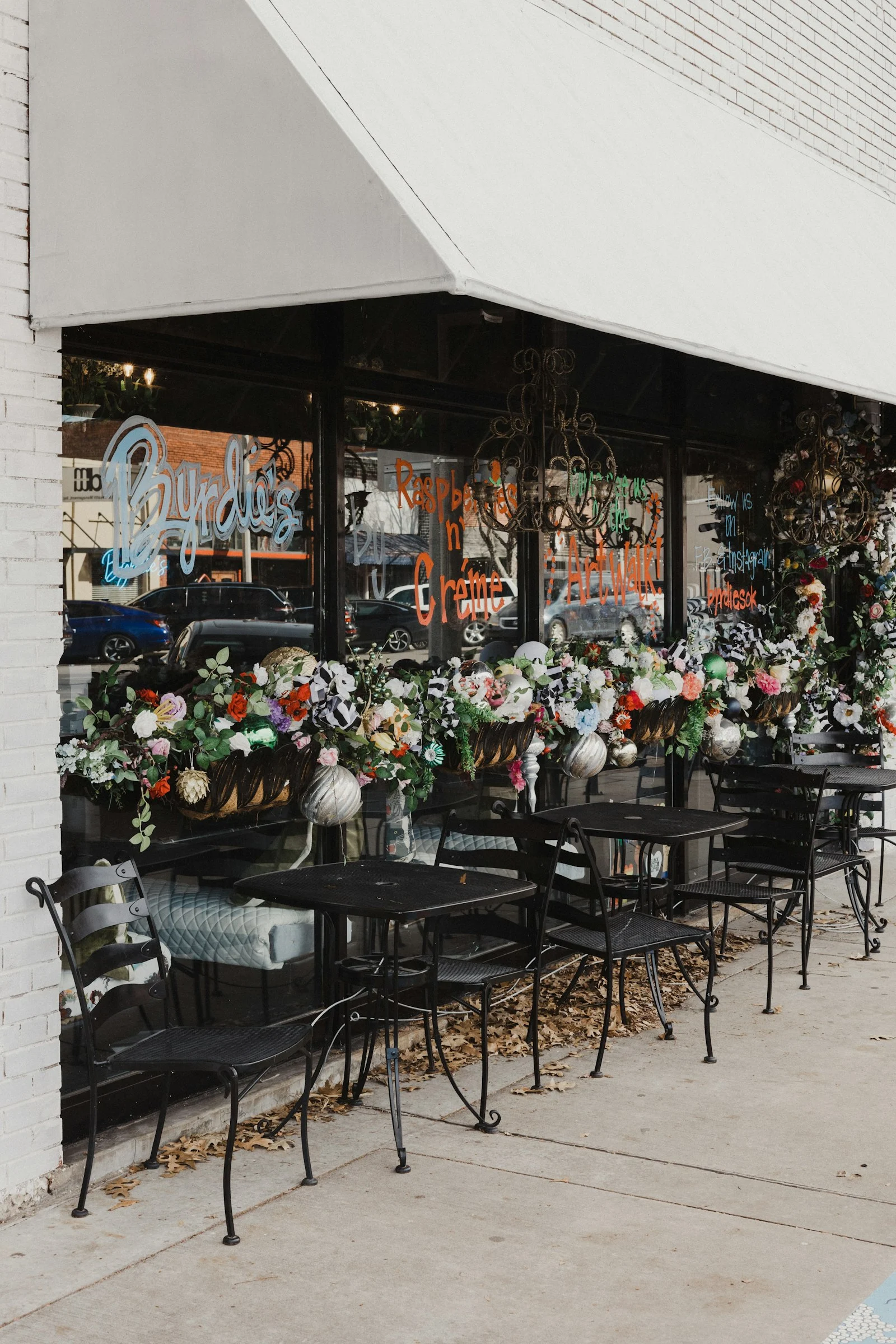 Tables et chaises installées devant la vitrine d’un fleuriste