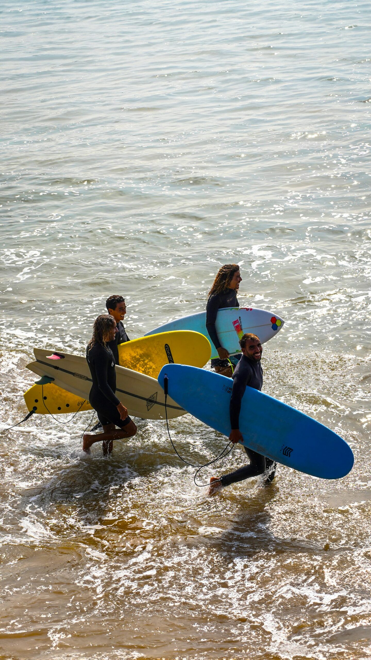tourisme-surfeurs-ocean Un groupe de surfeurs entre dans l’océan, planche sous le bras